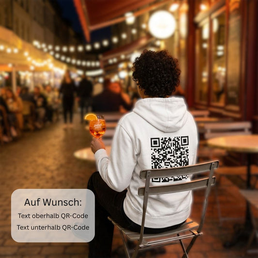 junge Fraumit Hoodie und Qr-Code auf dem Rücken sitzt im Café und trinkt Aperol